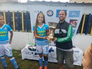 Matías Saldivar, organizador de la Copa Internacional Fútbol Rock de fútbol femenino, entregándole la Copa de Oro al Club Fuerza Cristal de Perú. 