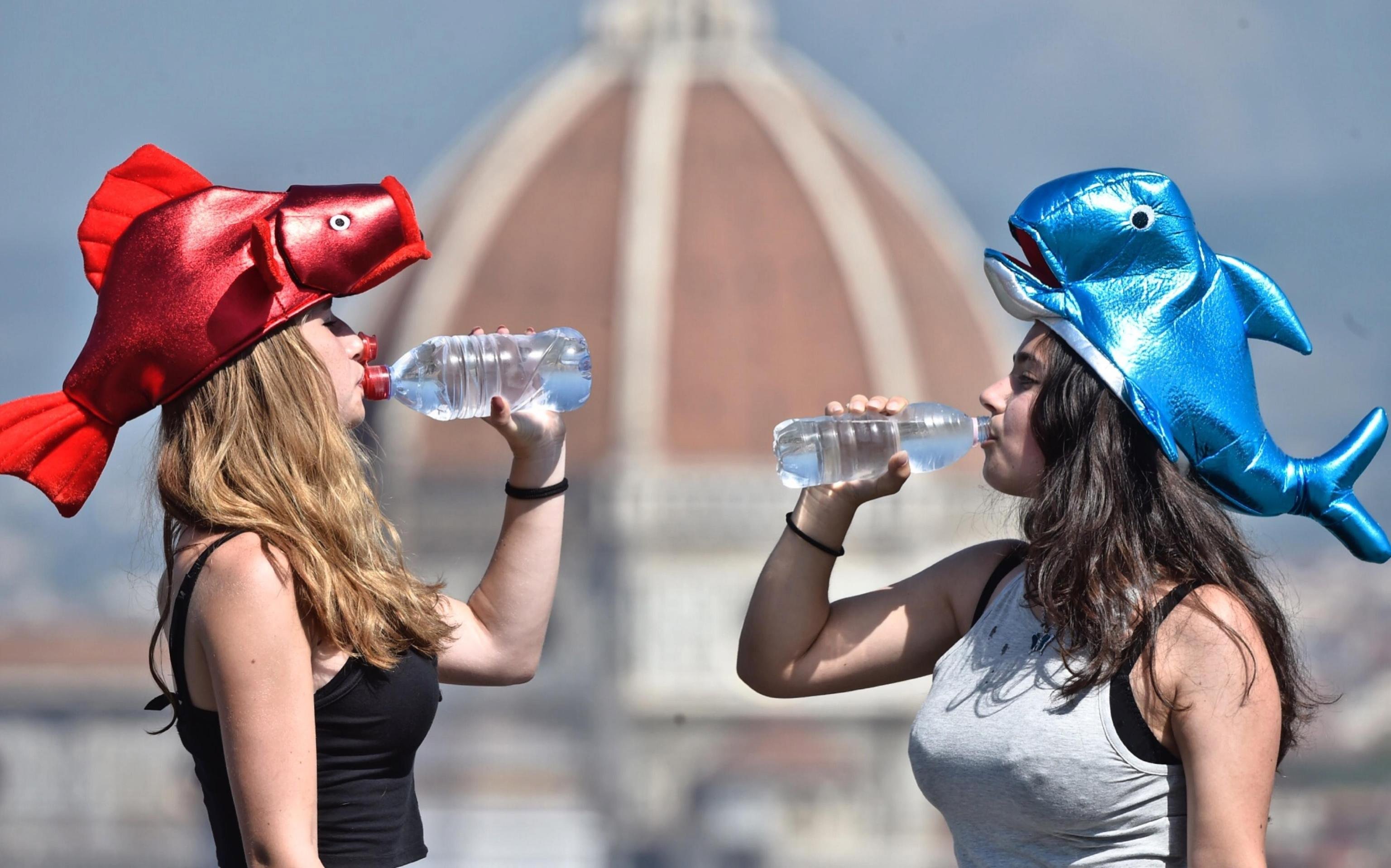 Dos chicas beben agua frente a la Catedral de Santa María del Fiore en Florencia. Foto: EFE/Maurizio Degl'Innocenti.