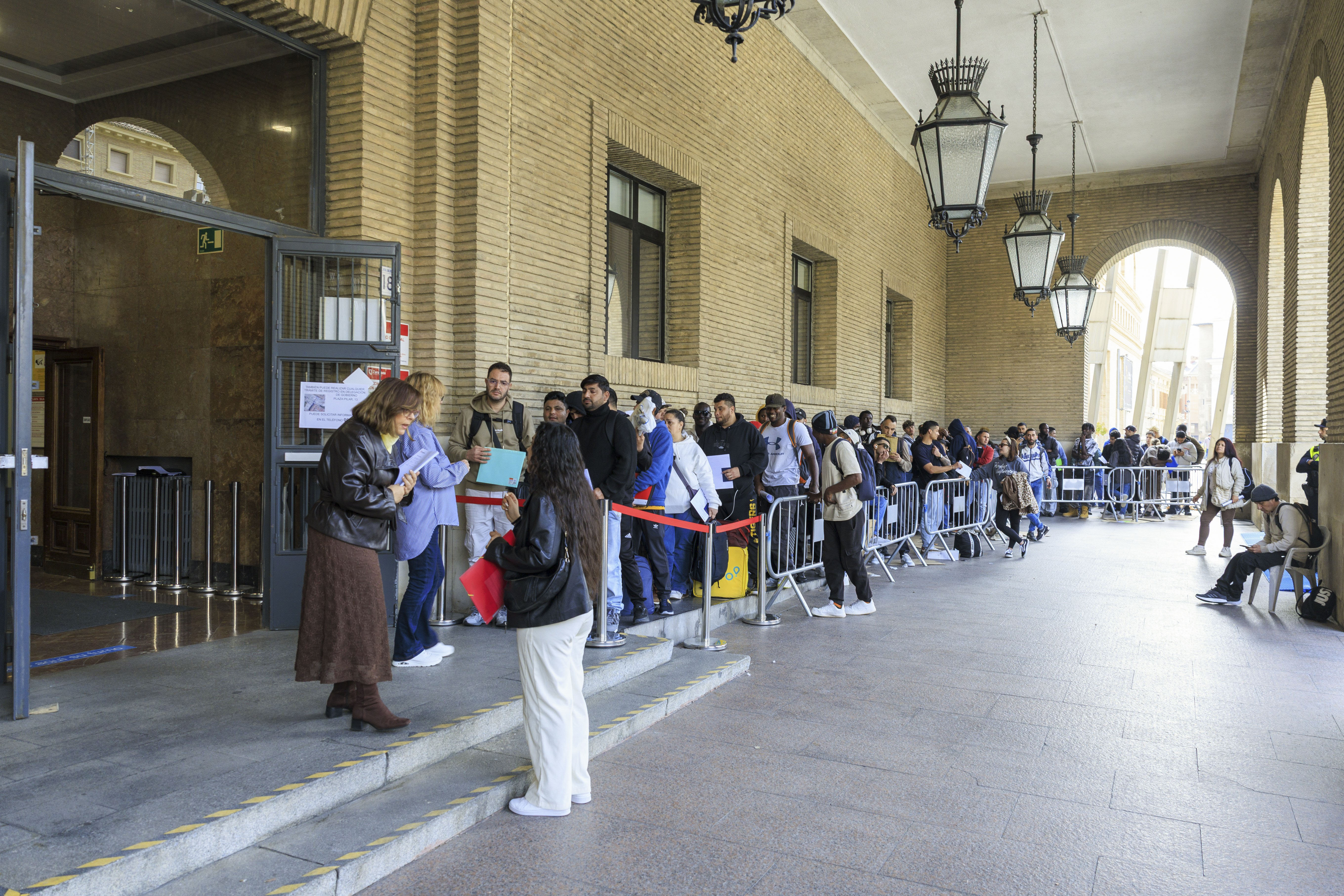 Como desde hace días, cientos de personas migrantes hacen cola en las puertas del Ayuntamiento de Zaragoza y de la Delegación de Gobierno, con la expectativa de poder reunir la documentación necesaria para regularizarse. Foto: EFE | Javier Cebollada.