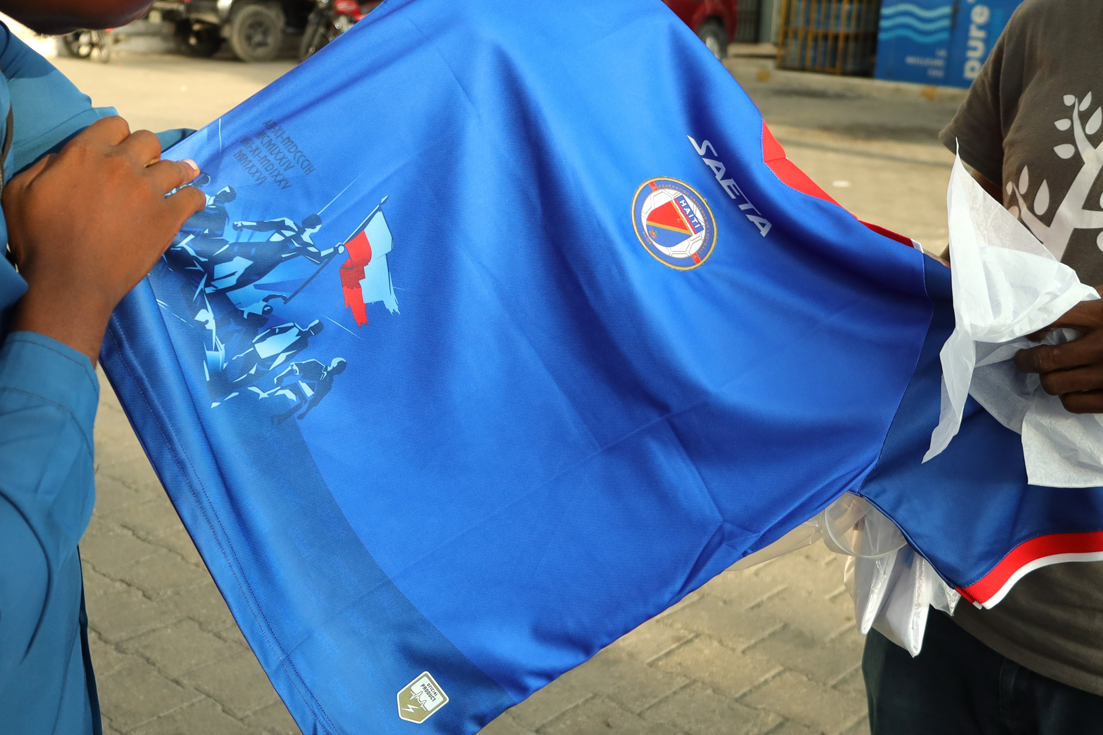 Una persona sostiene una camiseta de la selección de fútbol de Haití, en Puerto Príncipe. Foto: EFE | Patrice Noel.
