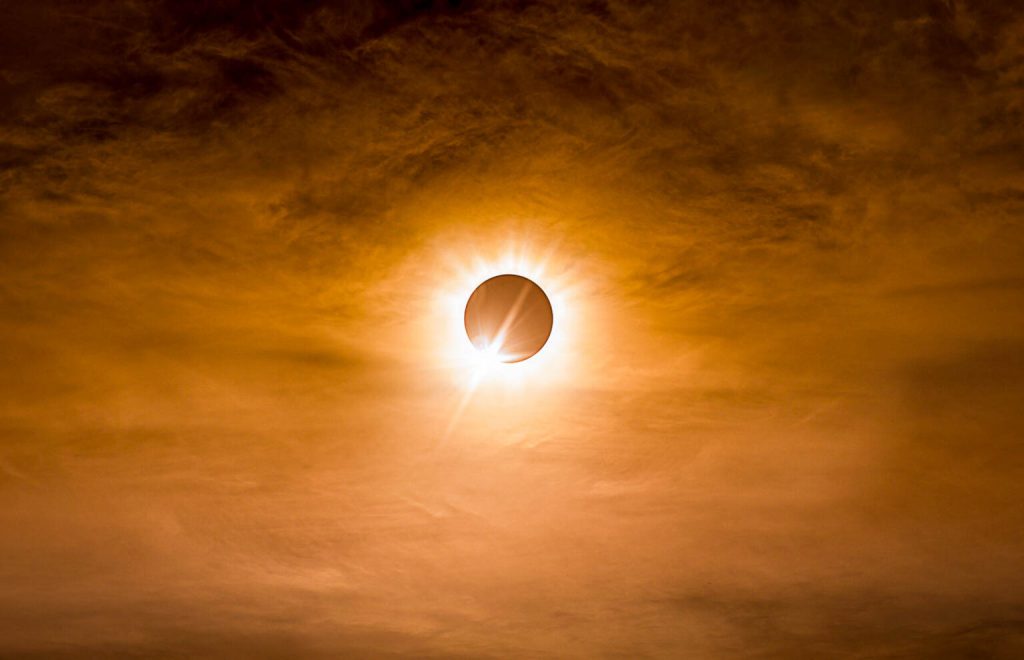 Total solar eclipse in dark red cloudy sky