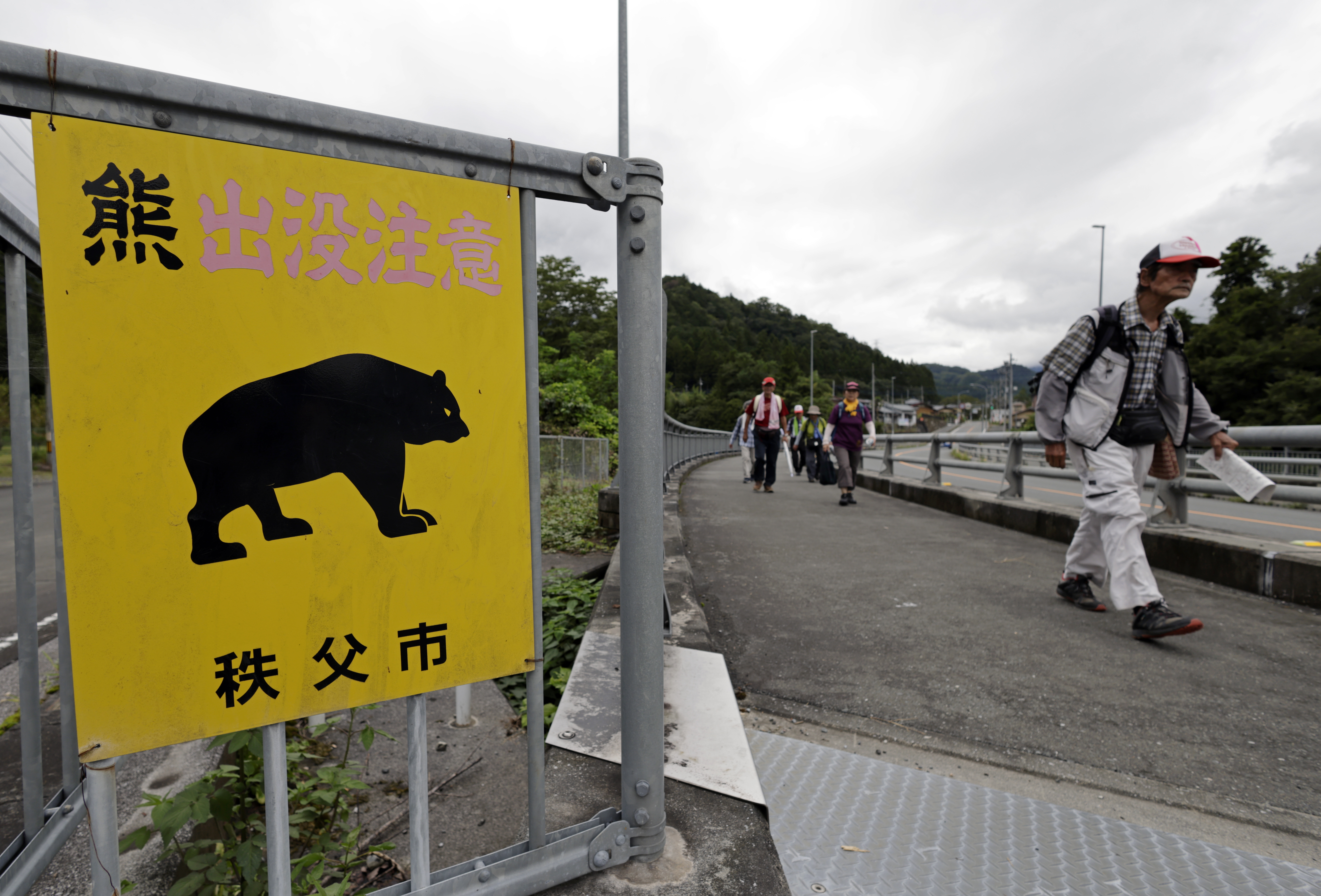 Un grupo de personas pasa junto a un letrero que dice "Cuidado con los osos" en Chichibu, prefectura de Saitama. Foto: EFE | EPA | Franck Robichon.