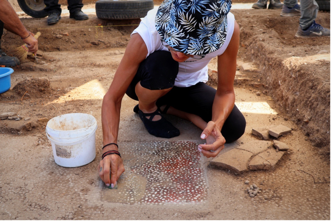 Una arqueóloga limpia un mosaico hallado en el suelo de una sala de banquetes descubierto en las excavaciones del yacimiento arqueólogico de Mieza. Foto: EFE | Ministerio de Cultura de Grecia.