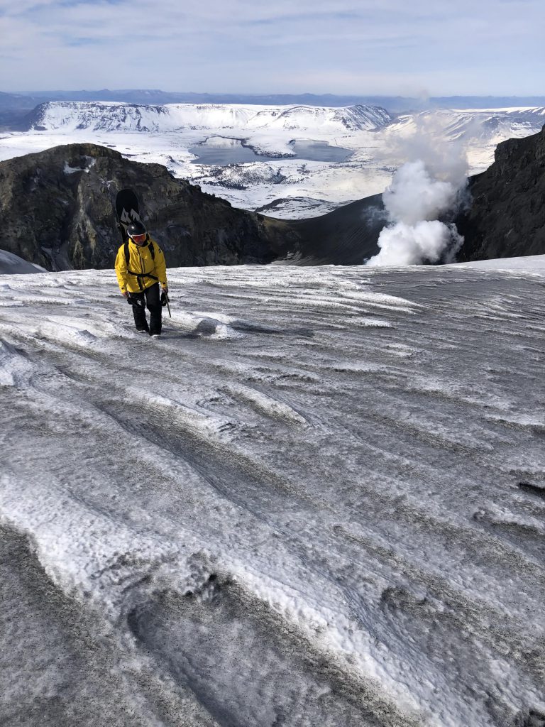 El barilochense Iñaki Odriozola (23) camina de regreso tras el hito de descender con su tabla por el volcán Copahue.