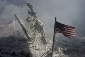 Am American flag flies near the base of the destroyed World Trade Center in New York, September 11, 2001. Planes crashed into each of the two towers, causing them to collapse.  REUTERS/Peter Morgan