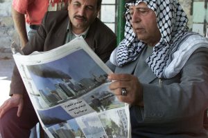 Palestinians read a Palestinian newspaper September 12, 2001, outside a shop in the West Bank city of Ramallah, showing the terror attacks in the USA. Governments around the world offered condolences to an America that looked more vulnerable than ever after Tuesday's terror attacks.      REUTERS/Nayef Hashlamoun