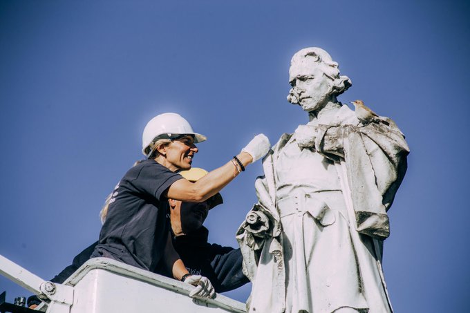 Constanza Addhiechi repara la escultura de Colón, con un pájaro posando sobre el hombro.