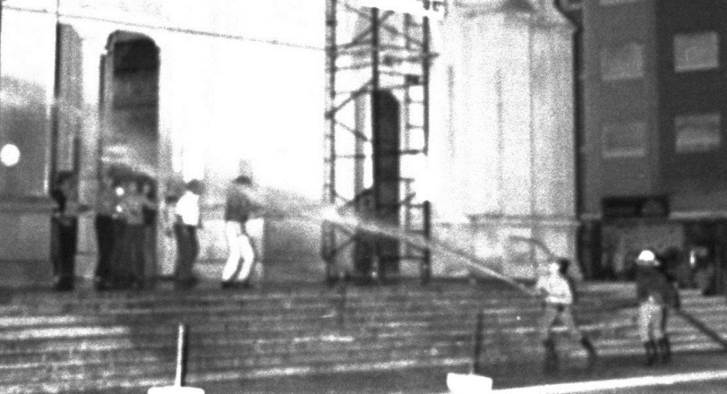 Bomberos arrojan agua contra un reducido grupo de manifestantes en la escalinata de la Catedral.