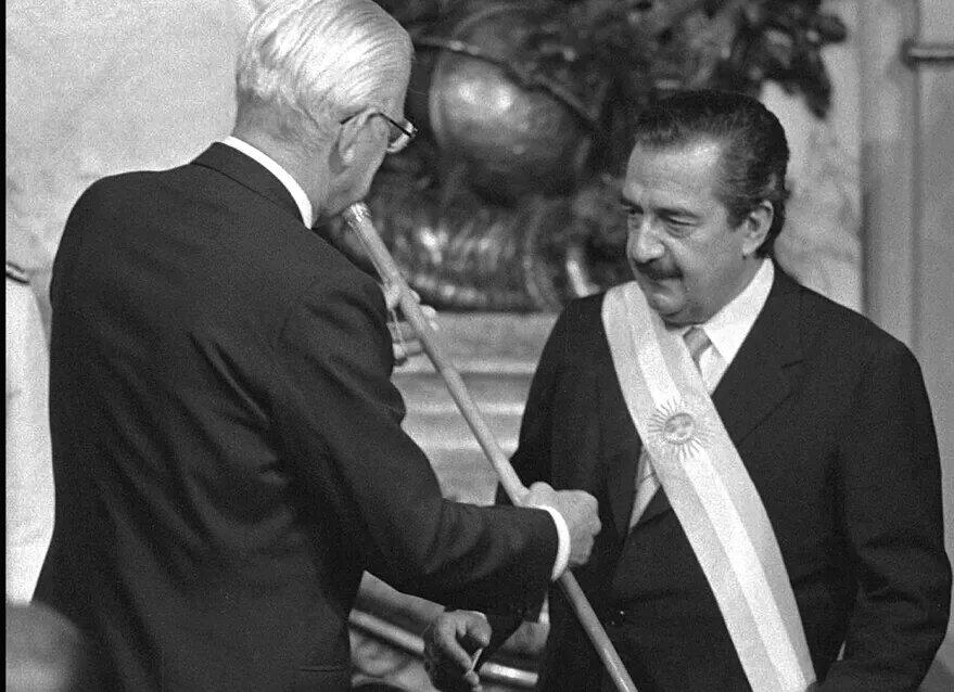 Alfonsín recibe la banda y el bastón presidencial de manos del último presidente de facto, el general Reinaldo Bignone.