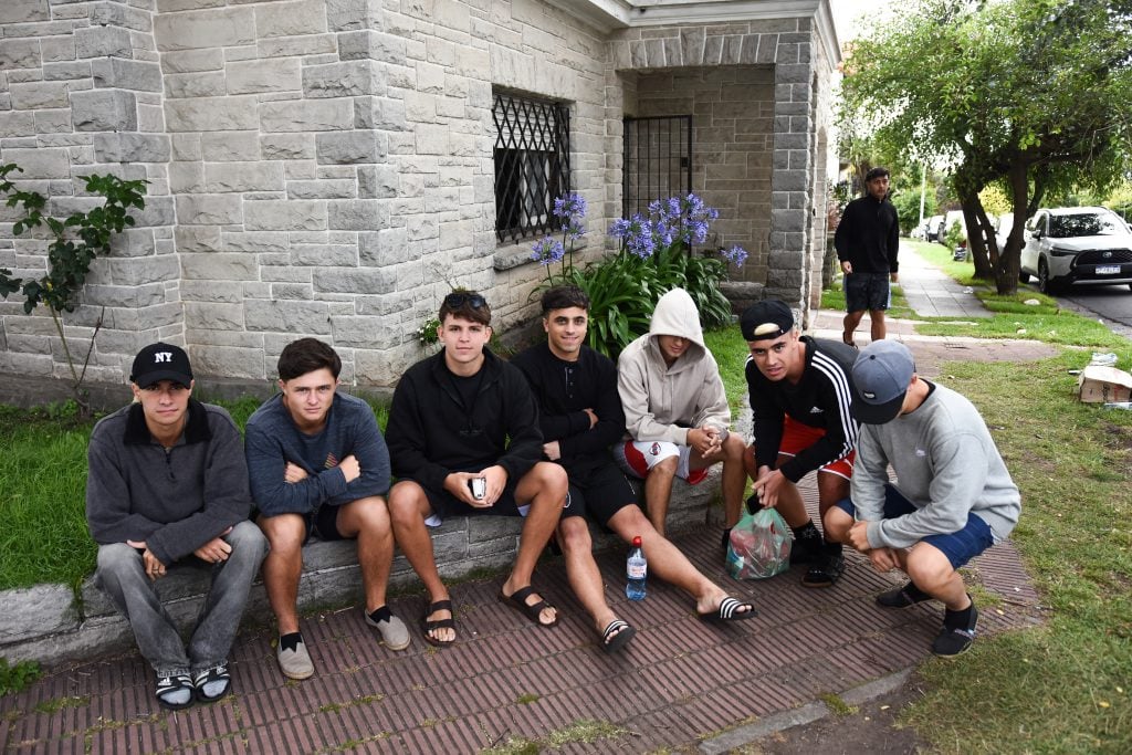 Un gran grupo de 13 rosarinos, como Tobías y Franco, toman unos mates en la vereda de Playa Grande.