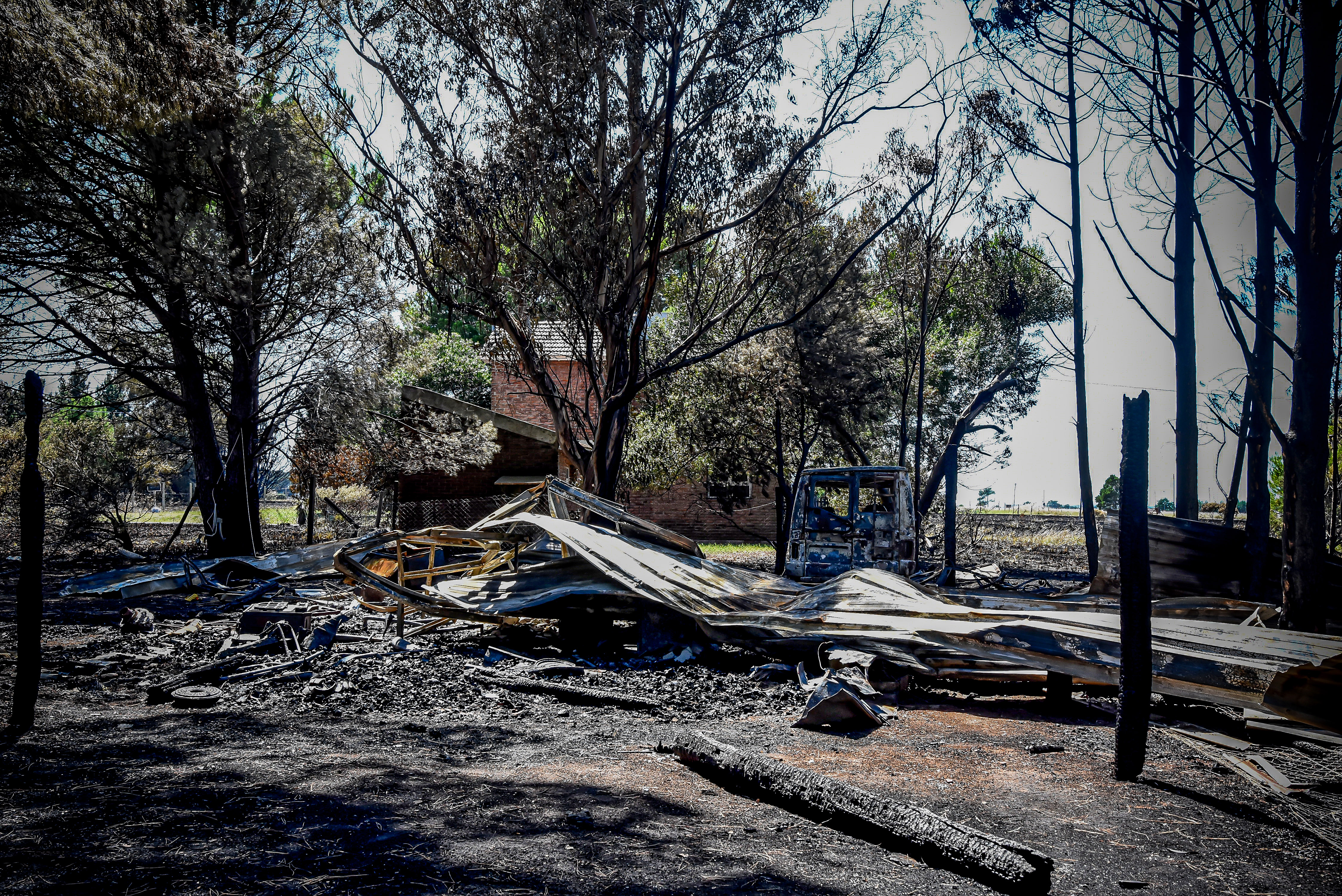Restos del techo de una vivienda prendida fuego y un vehículo calcinado.