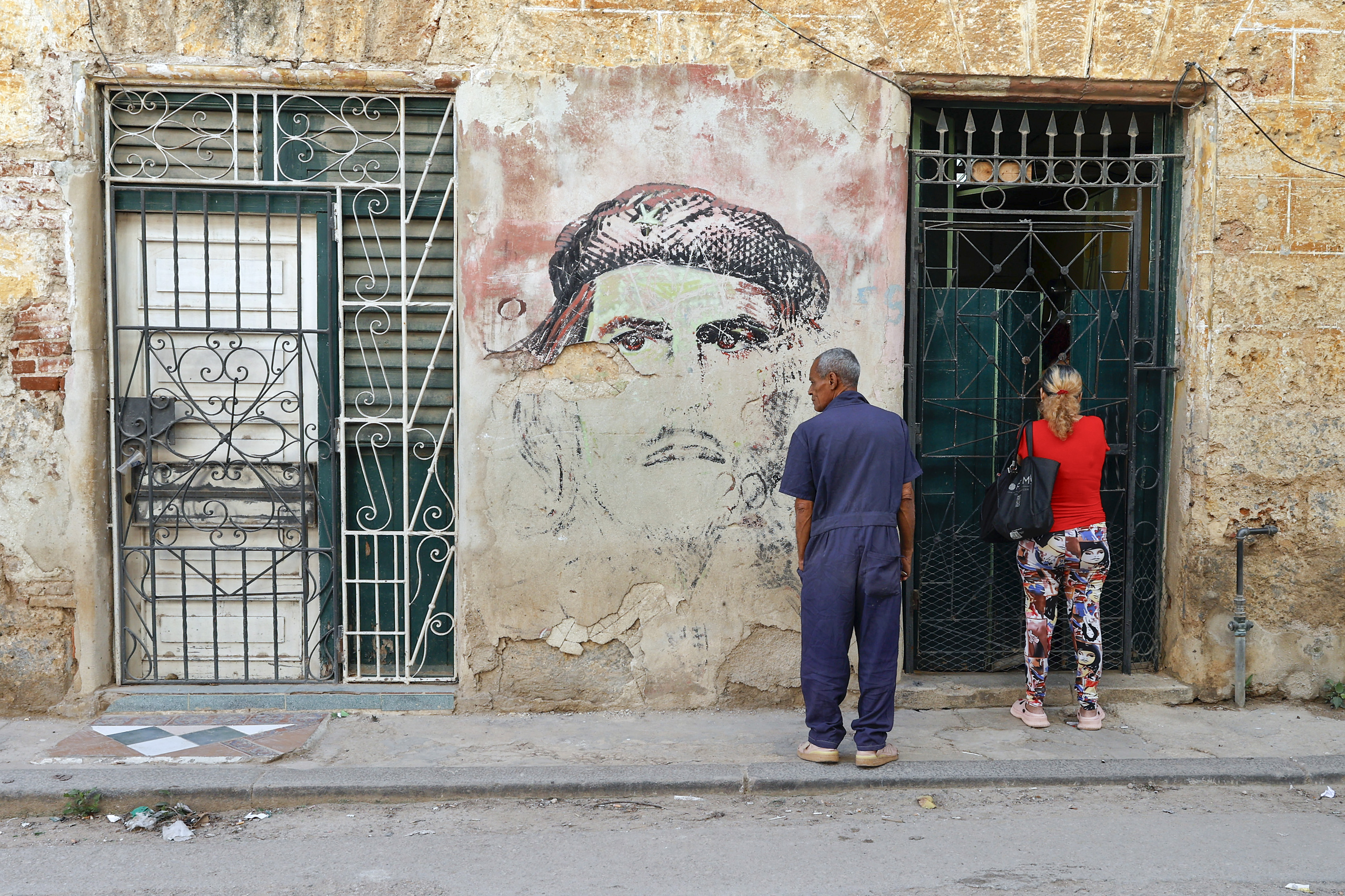 Personas esperan frente a un mural con la imagen de Ernesto 'Che' Guevara en La Habana, Cuba. Foto: EFE | Ernesto Mastrascusa.