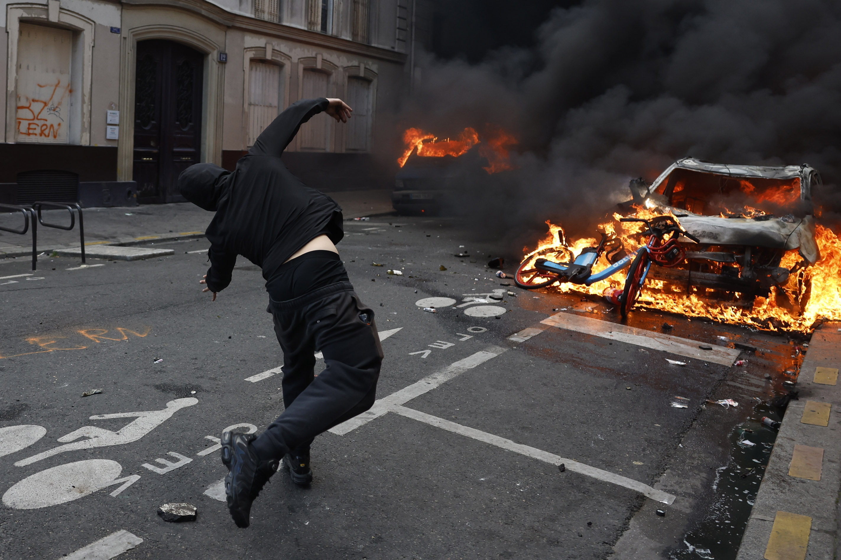 Un manifestante lanza objetos contra un auto en llamas durante una protesta en París. Foto: EFE | EPA | Mohammed Badra.